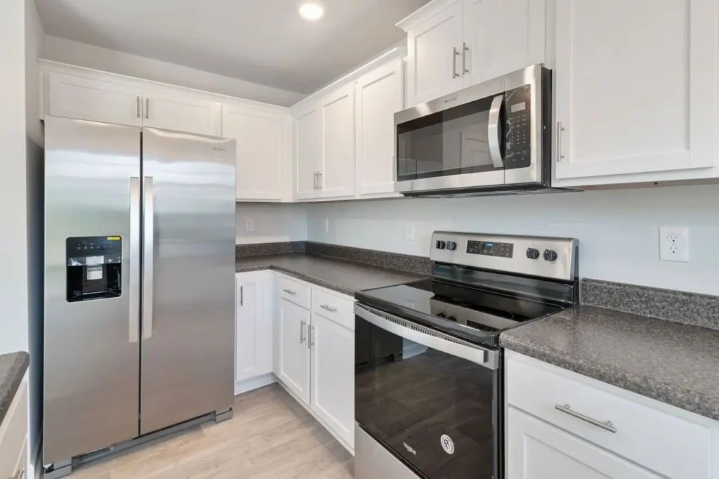 Modern kitchen with white cabinets, stainless steel appliances, and gray granite countertops