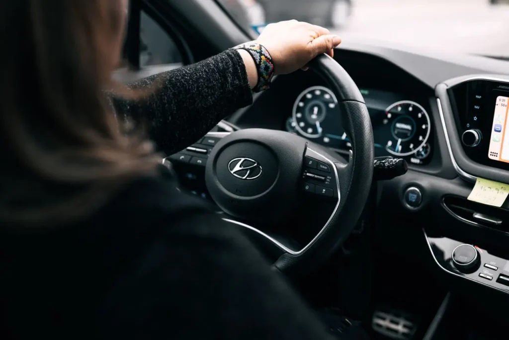 Person's hand on steering wheel of Hyundai vehicle with dashboard and touchscreen visible