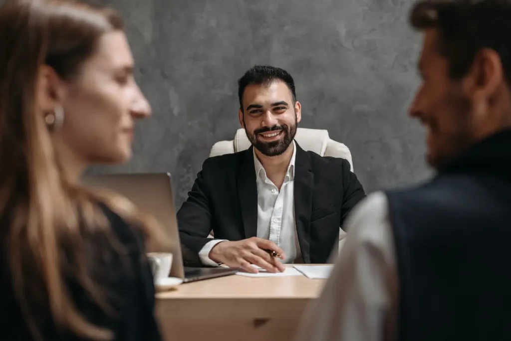 Professional businessman smiling at couple during consultation meeting in modern office